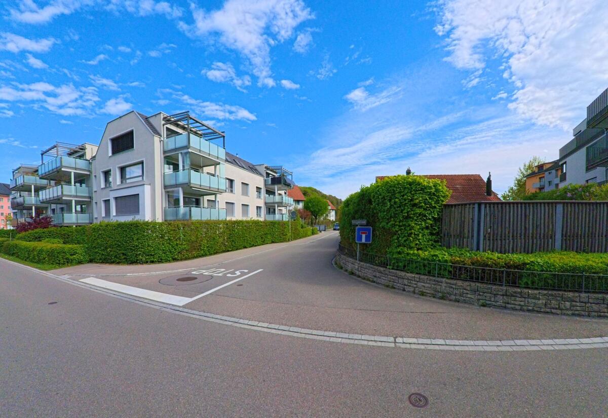  In Pfungen im Kanton Zürich, PLZ 8422, verläuft eine Seitenstrasse mit moderner Wohnbebauung und gepflegter Begrünung entlang eines Wohnquartiers.