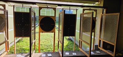 In Hinwil (8342, Kanton Zürich) sind mehrere Zielscheiben eines Pistolenschiessstands mit Schutzrahmen und Blick auf die Aussenanlage zu sehen.