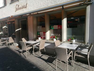 Vor der Pizzeria Firenze in Steckborn (8266, Kanton Thurgau) stehen auf dem Pflasterbelag Tische und Stuehle fuer Gaeste im Aussenbereich bereit.