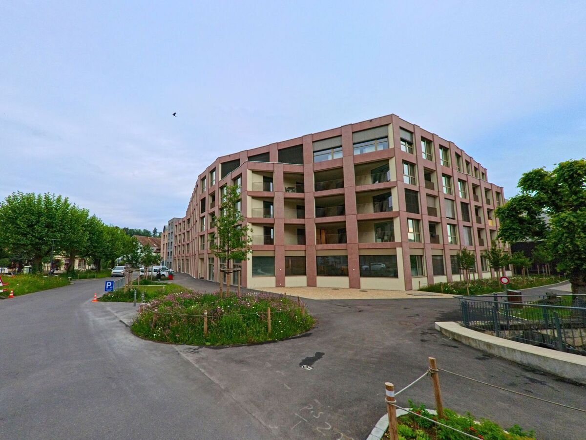 In Porrentruy (2900, Kanton Jura) befindet sich ein moderner Wohnkomplex mit klarer Geometrie und grosszügigen Balkonen an einer neu gestalteten Zufahrtsstrasse.