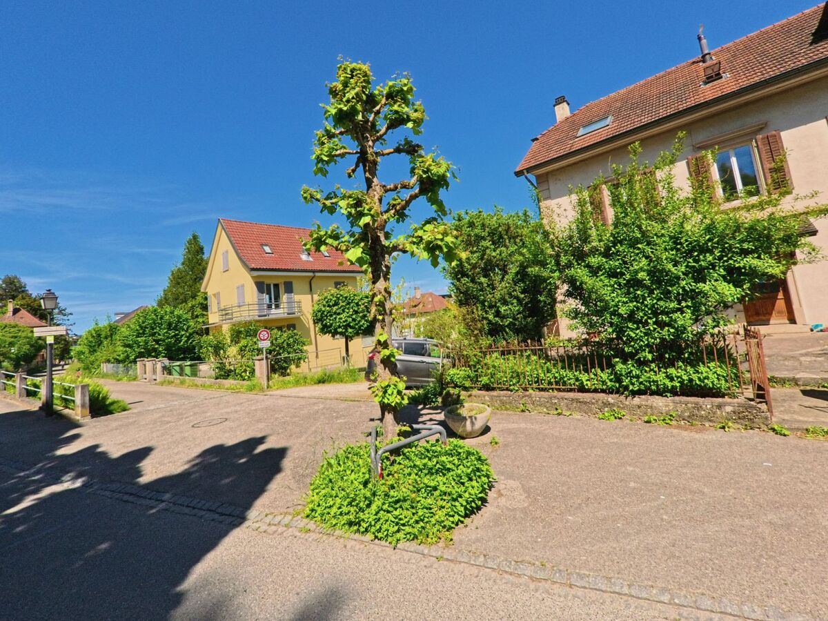 In einem grünen Wohnviertel von Porrentruy (2900, Kanton Jura) säumen Einfamilienhäuser mit roten Dächern eine kleine Seitenstrasse mit verkehrsberuhigtem Charakter.