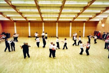In einem Saal in Pratteln (4133, Kanton Baselland) tanzen Paare des Prattler Tanzclubs gemeinsam auf dem Parkettboden.