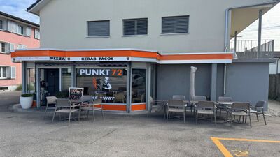 Das Lokal Punkt72 in Berg TG (8572, Kanton Thurgau) verfügt über eine kleine Terrasse mit Sitzplätzen vor der Fassade, die mit orangen Akzenten gestaltet ist.
