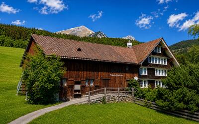 Das Puppentheater Wildhaus befindet sich in Wildhaus-Alt St. Johann (9658, Kanton St. Gallen) in einem traditionellen Holzhaus vor einer markanten Bergkulisse.