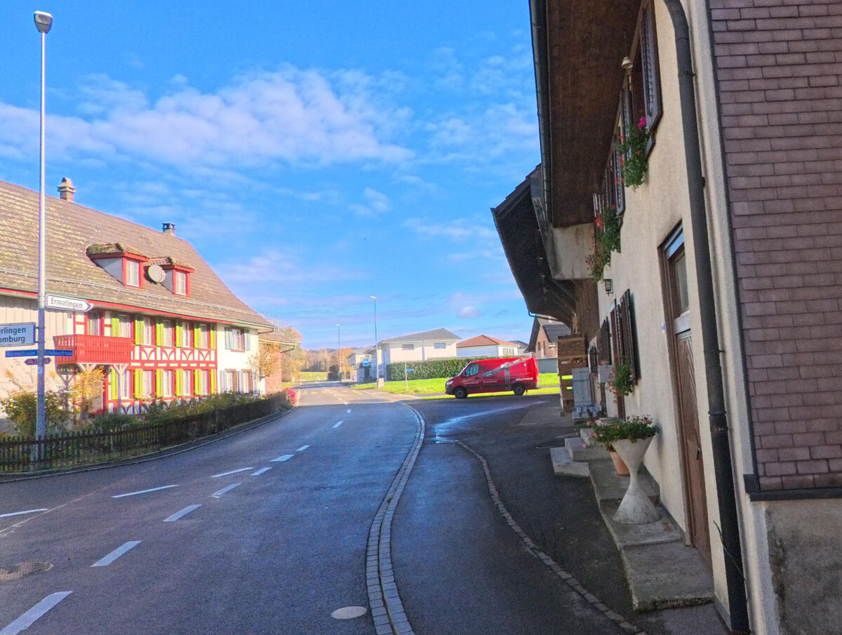 Eine kurvige Dorfstrasse mit geschlossener Bebauung verlaeuft durch Raperswilen (8558, Kanton Thurgau).