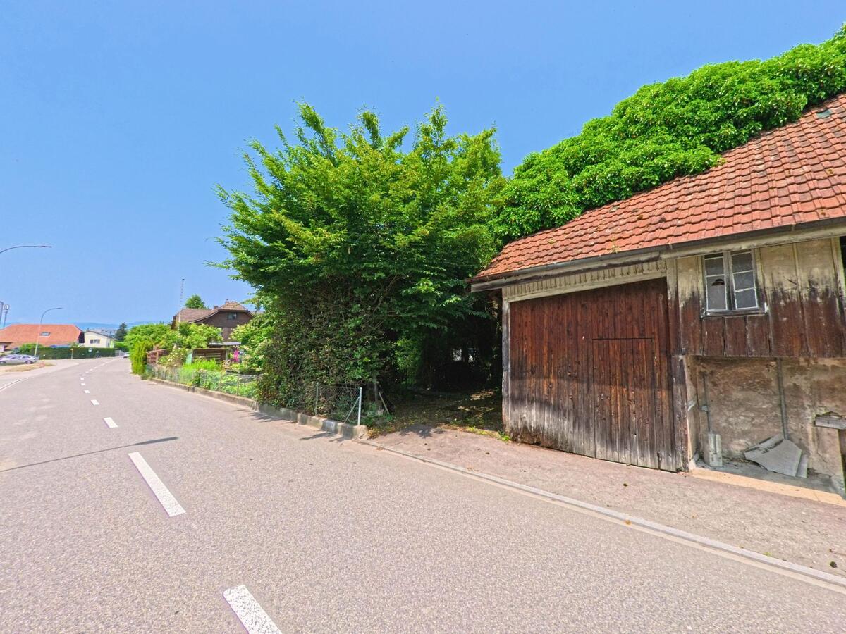 Ein altes Holzgebäude in Recherswil (4565, Kanton Solothurn) steht an einer ruhigen Straße, umgeben von üppigem Grün und Bäumen.