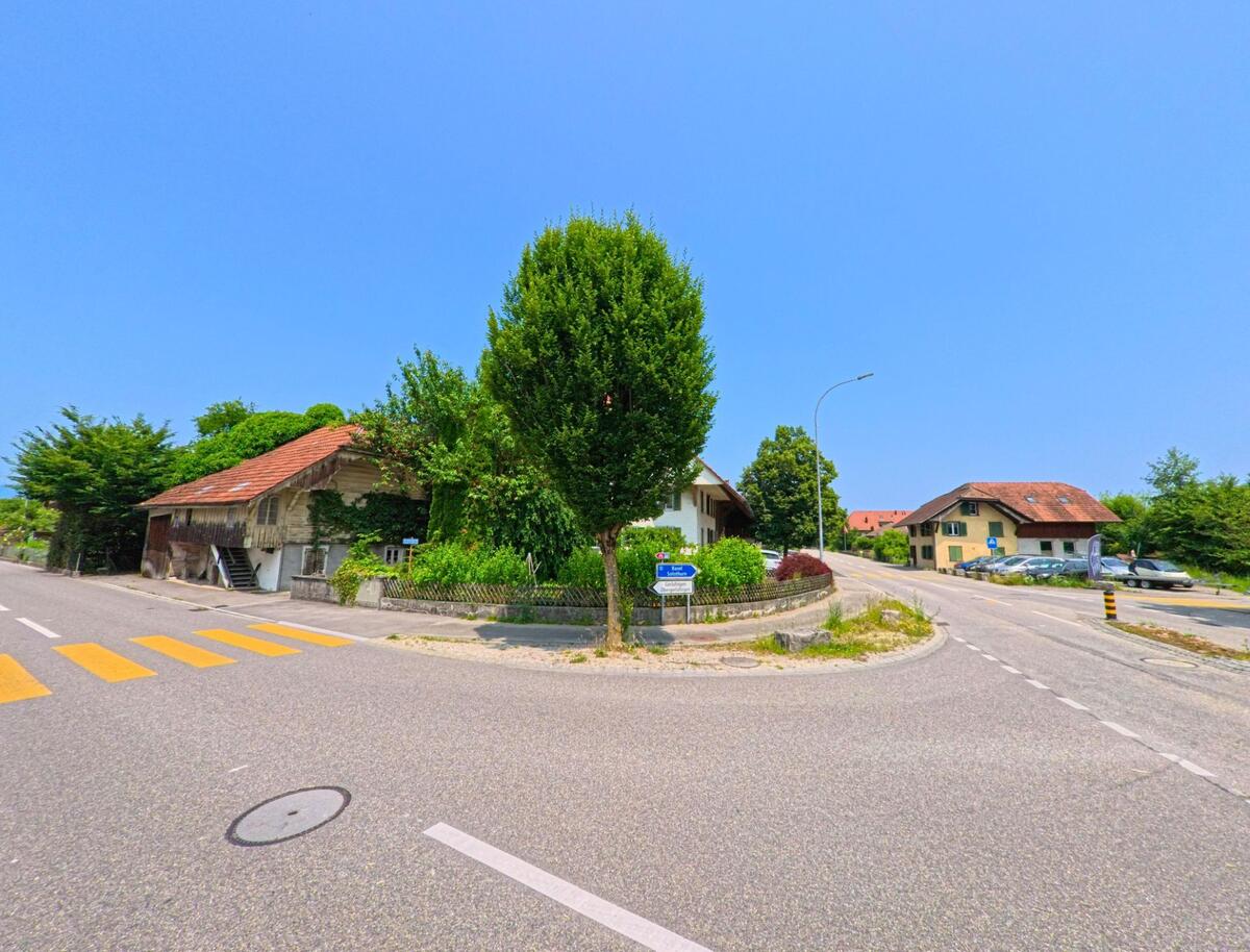 In Recherswil (4565, Kanton Solothurn) zeigt sich eine malerische Straßenecke mit einem alten, von Efeu bedeckten Gebäude und einer angrenzenden grünen Wiese.