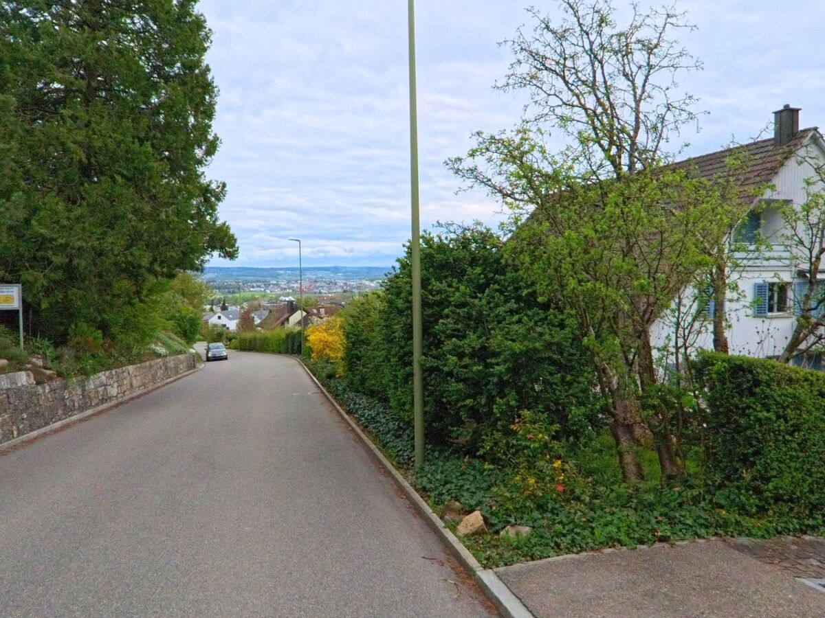 In Regensberg, PLZ 8158 im Kanton Zürich, fällt eine ruhige Wohnstrasse sanft ab und eröffnet eine weite Sicht über das dicht bebaute Zürcher Unterland.