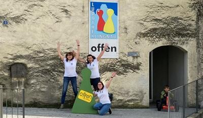 In Klingnau (5313, Kanton Aargau) posieren drei Mitarbeiterinnen der Regionalen Ludothek Klingnau fröhlich vor dem Eingang und einem grossen Spielfigur-Symbol.