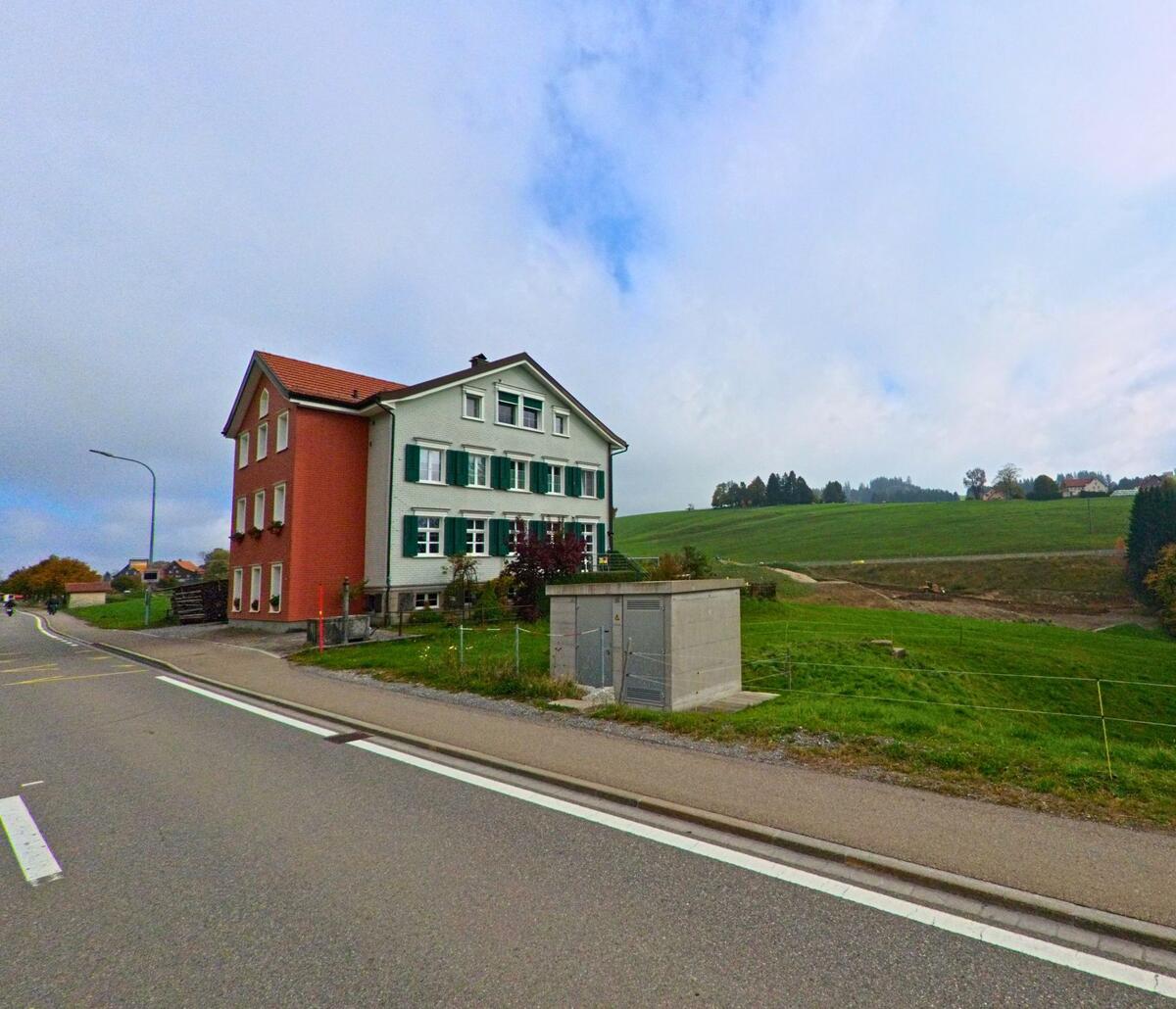 Ein Wohnhaus liegt am Rand einer offenen Wiese an der Durchgangsstrasse von Rehetobel (9038, Kanton Appenzell Ausserrhoden).