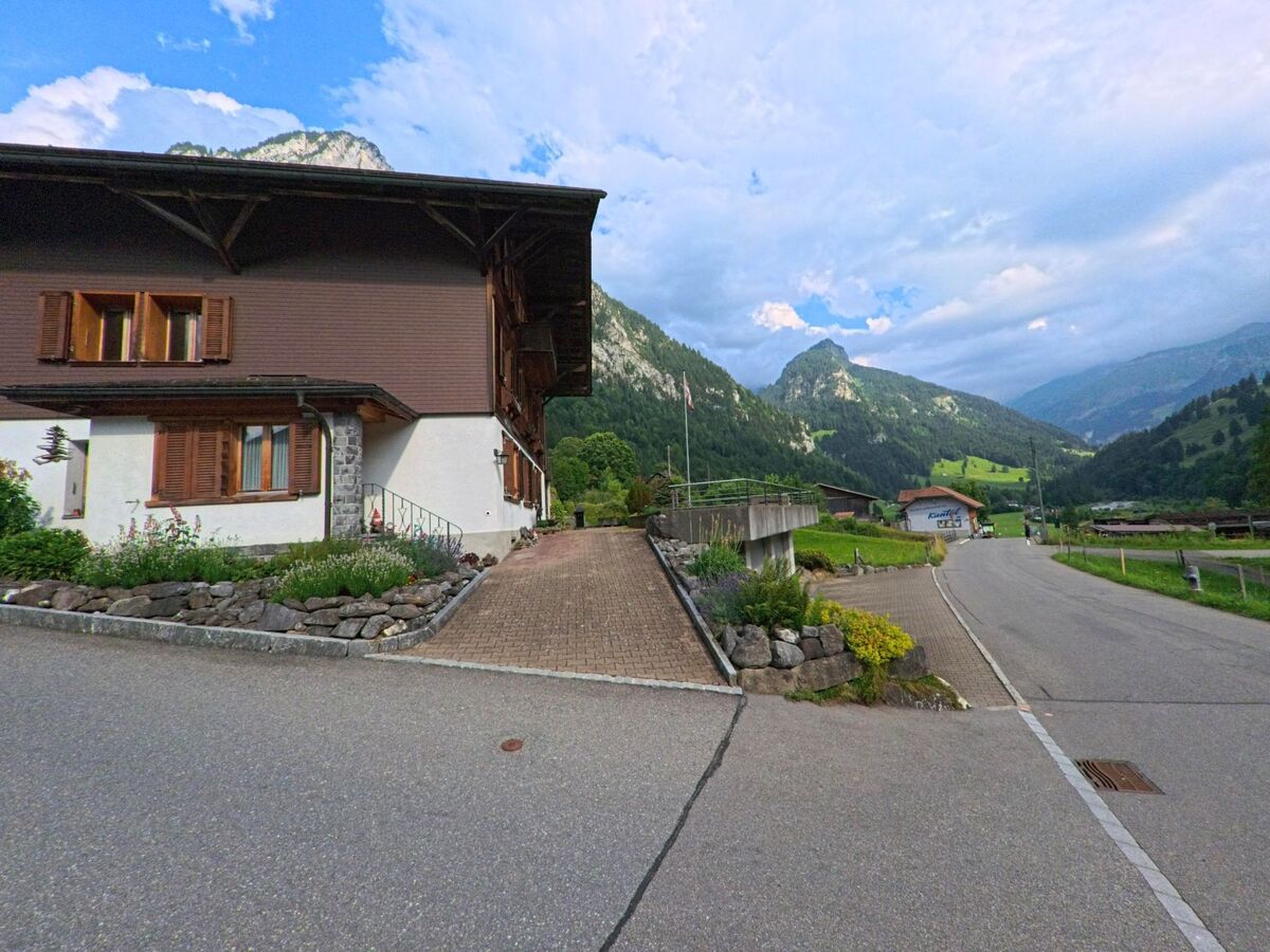 In Reichenbach im Kandertal (3723, Kanton Bern) führt eine schmale Strasse vorbei an Wohnhäusern und Wiesen in ein von steilen Hängen und bewaldeten Bergen umgebenes Seitental.