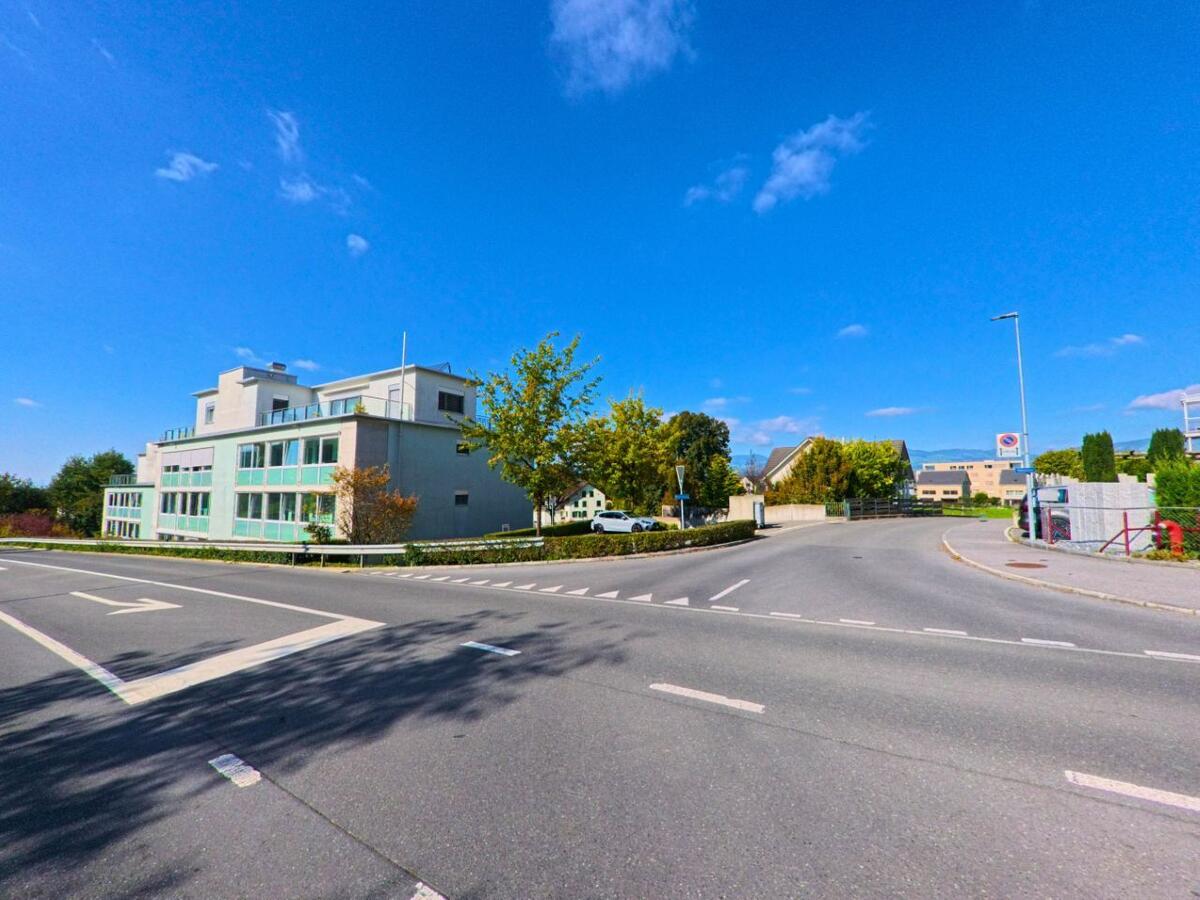 Vor einem modernen Wohngebäude öffnet sich eine übersichtliche Kreuzung in Reichenburg (8864, Kanton Schwyz).