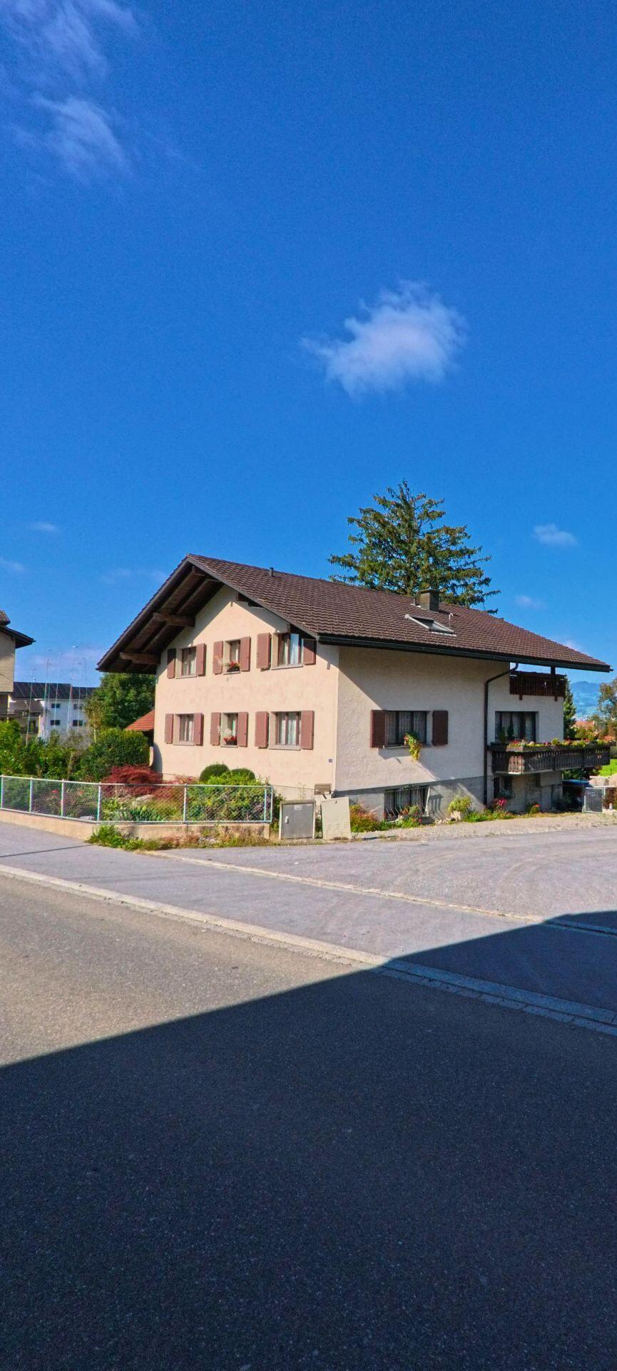 Ein traditionelles Wohnhaus mit Vorplatz liegt an einer Nebenstrasse in Reichenburg (8864, Kanton Schwyz).