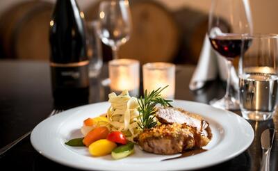 Im Restaurant Commenda in Hitzkirch (6285, Kanton Luzern) liegt ein fein angerichtetes Gericht mit Fleisch, Nudeln und Gemuese auf einem gedeckten Tisch.