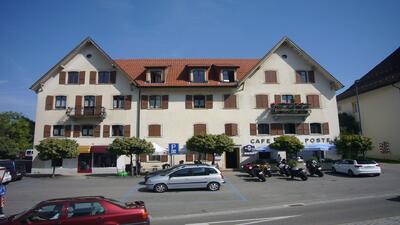 Das Restaurant de la Poste in Saignelégier (2350, Kanton Jura) befindet sich in einem mehrstöckigen Gebäude mit roten Fensterläden und Terrasse vor dem Eingang.