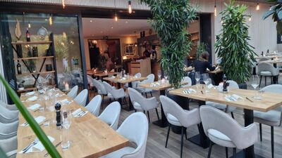 Im Restaurant Pizzeria Bellevue in Ittigen (3063, Kanton Bern) stehen hell eingerichtete Tische mit modernen Stuehlen und gruene Pflanzen sorgen fuer eine freundliche Atmosphaere.