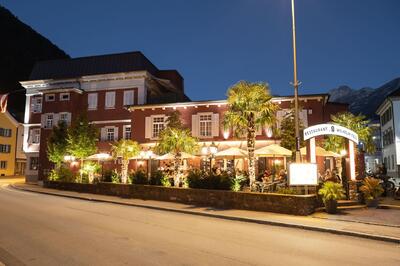 In Altdorf UR (6460, Kanton Uri) leuchtet am Abend das Restaurant Wilhelm Tell mit seiner Terrasse unter Palmen und hell erstrahlten Laternen.