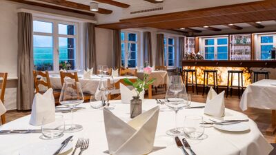 In Berg (9305, Kanton St. Gallen) zeigt das Restaurant Sternen einen elegant gedeckten Gastraum mit Holzdecken, grossen Fenstern und einer beleuchteten Bar.