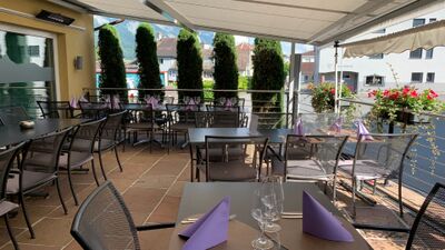 Auf der Terrasse des Restaurant Sternen in Flums (8890, Kanton St. Gallen) stehen gedeckte Tische mit lilafarbenen Servietten und Blick auf die umliegenden Häuser.