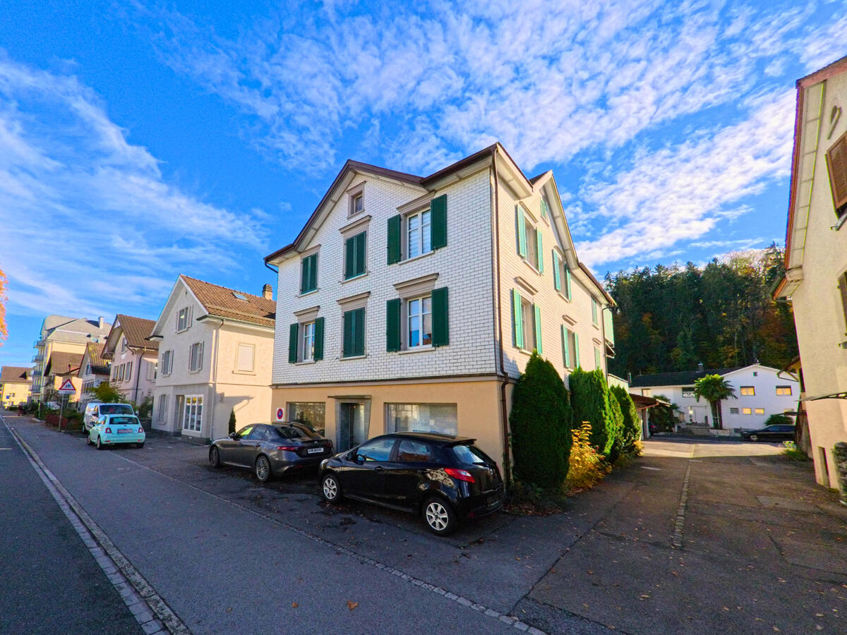 Ein Mehrfamilienhaus mit Parkplaetzen steht an einer Quartierstrasse in Rheineck (9424, Kanton St. Gallen).