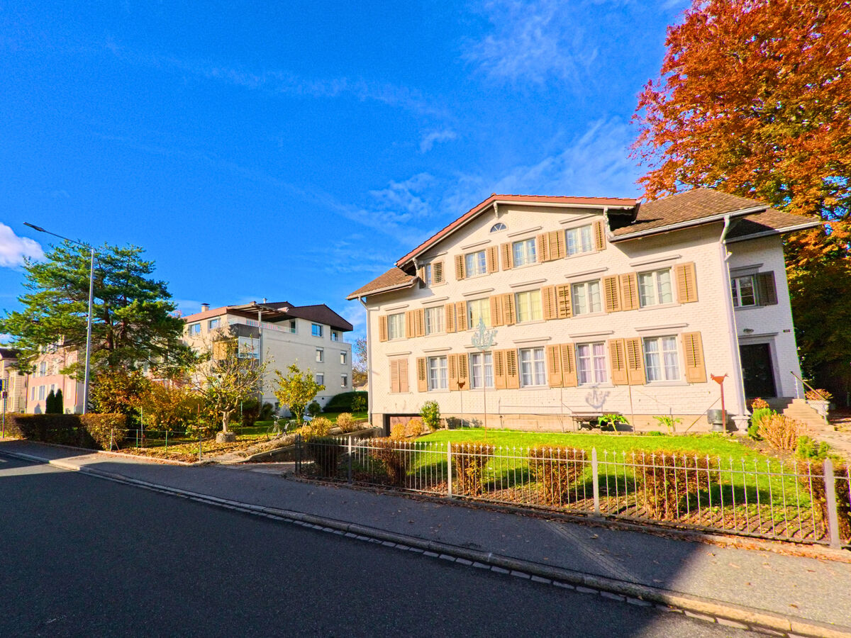 Ein Wohnhaus mit heller Fassade liegt an einer sonnigen Strasse in Rheineck (9424, Kanton St. Gallen).
