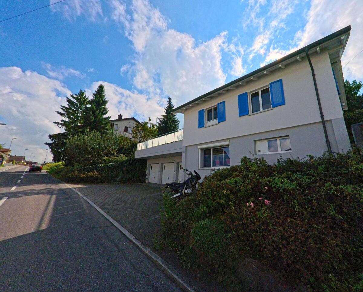 Ein Wohnhaus mit blauen Fensterlaeden liegt an einer ruhigen Strasse in Rickenbach (6221, Kanton Luzern).