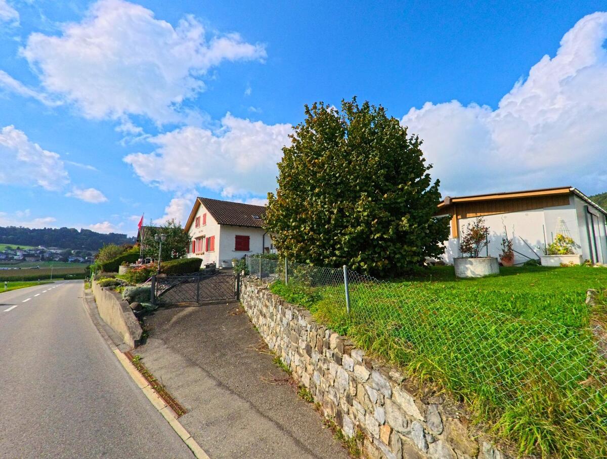 Ein Haus mit steinerner Stützmauer grenzt an eine schmale Zufahrt in Rickenbach (6221, Kanton Luzern).