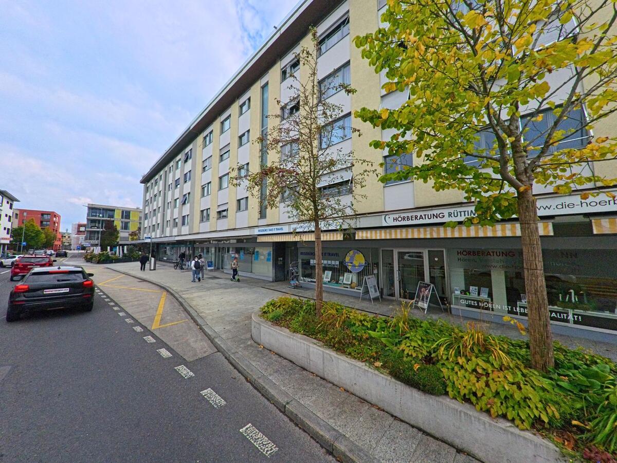 Mehrere Geschäfte reihen sich entlang eines Gehwegs in einem Wohn- und Geschäftshaus in Risch (6343, Kanton Zug).