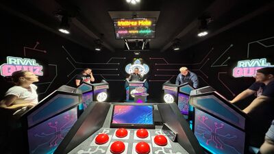 Im Rival Quiz Jura in Courtételle (2852, Kanton Jura) stehen Teilnehmende an beleuchteten Spielpulten und nehmen an einem interaktiven Quizduell teil.