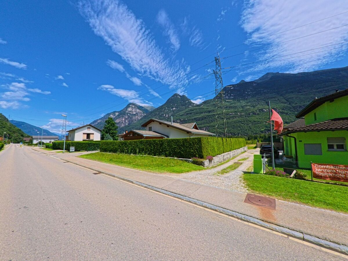 Entlang einer ruhigen Strasse in Riviera (6526, Kanton Tessin) stehen Einfamilienhäuser mit gepflegten Gärten und Blick auf die umliegenden Berge.