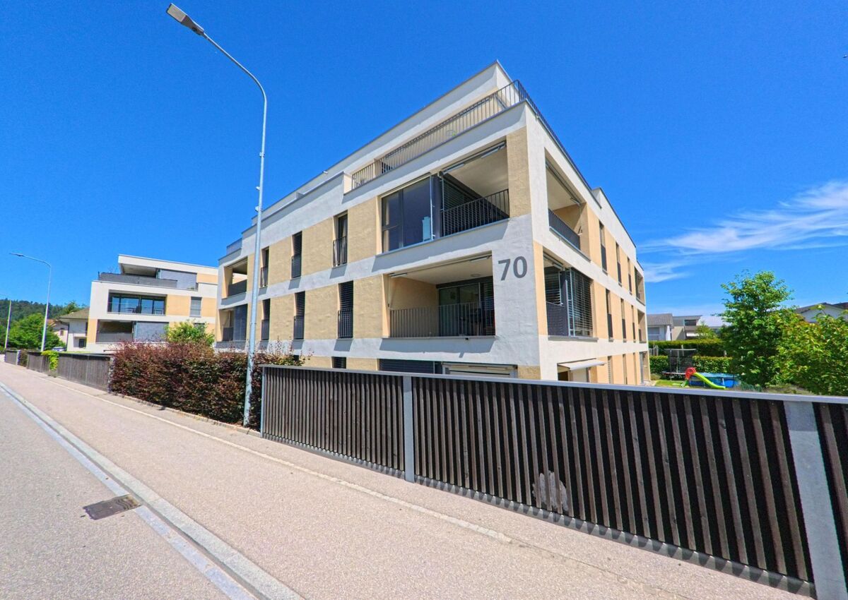 In Roggwil (4914, Kanton Bern) reihen sich moderne Mehrfamilienhaeuser mit grossen Balkonen und klarer Fassadengestaltung entlang einer ruhigen Strasse.