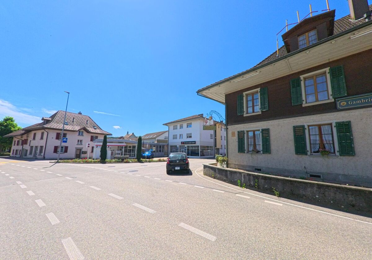In Roggwil (4914, Kanton Bern) praegen traditionelle und moderne Gebaeude mit Laeden und Gaststaetten das Ortsbild entlang einer ruhig verlaufenden Strasse.
