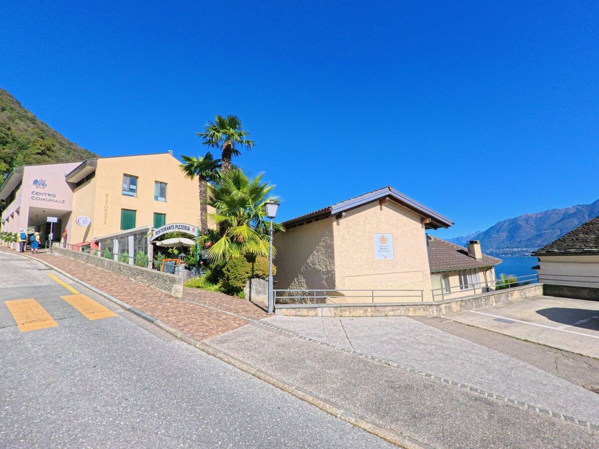In Ronco sopra Ascona (6622, Kanton Tessin) steht das Gemeindezentrum mit Palmen und Blick auf den Lago Maggiore an einer sonnigen Strasse.