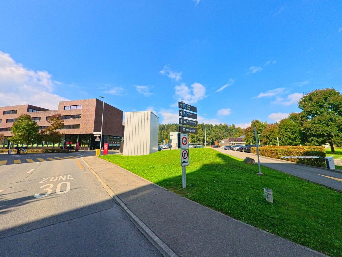 Zwischen Wegen und Rasenflächen zeigt sich ein zeitgemässes Gebäudeensemble in Root (6037, Kanton Luzern).