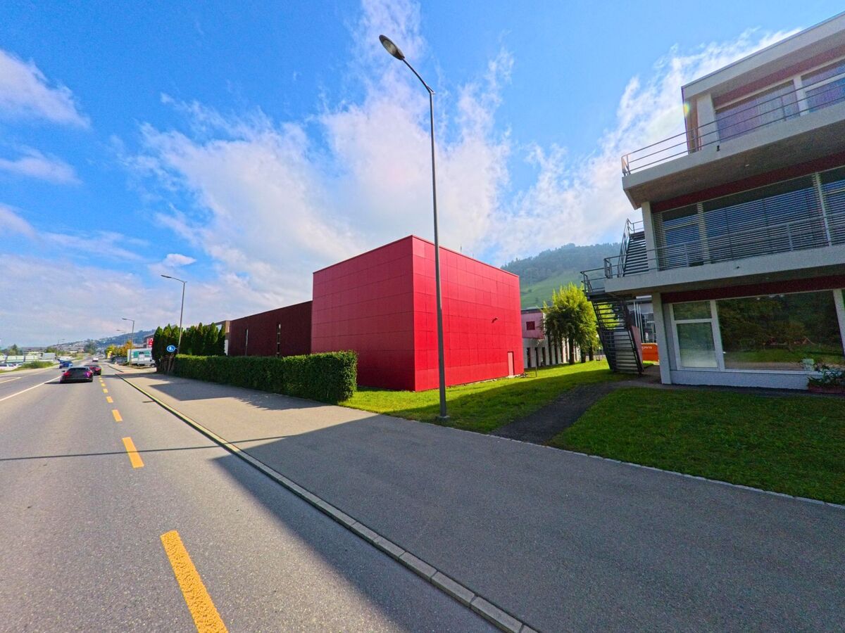 Ein markantes rotes Gebäude liegt direkt an einer Fahrbahn in Root (6037, Kanton Luzern).