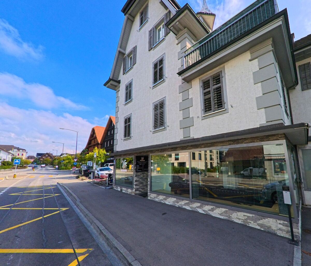 Ein traditionelles Gebäude mit Ladenfront prägt einen zentralen Strassenabschnitt in Root (6037, Kanton Luzern).