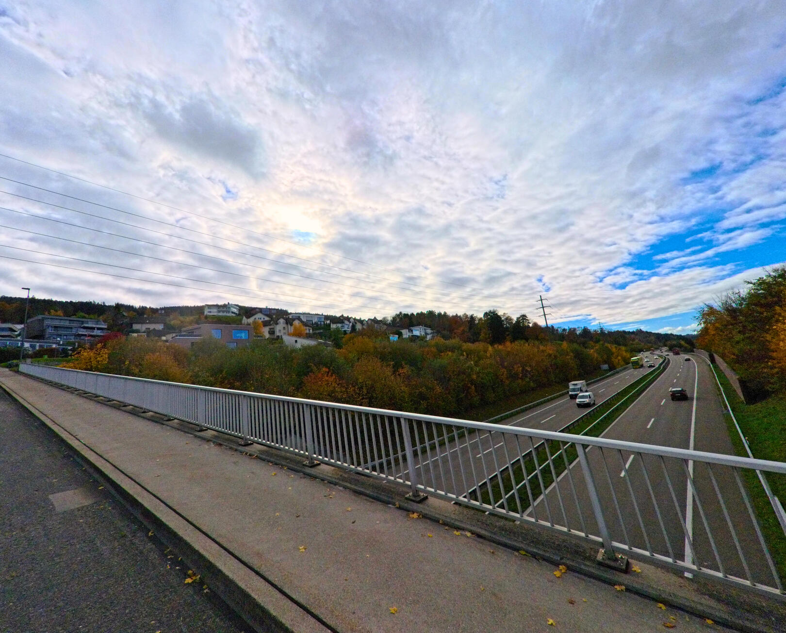 Von einer Bruecke aus bietet sich in Rorschacherberg (9404, Kanton St. Gallen) ein weiter Blick ueber eine mehrspurige Strasse, bewaldete Haenge und verstreute Wohnhaeuser.