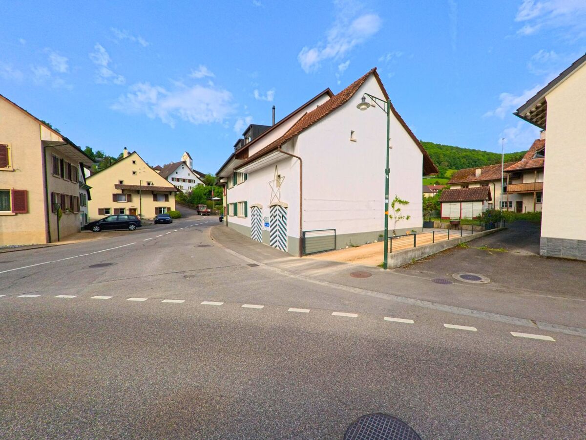 Im Zentrum von Rothenfluh (4467, Kanton Baselland) treffen mehrere Strassen aufeinander, umgeben von traditionellen Haeusern und mit Blick auf die Kirche im