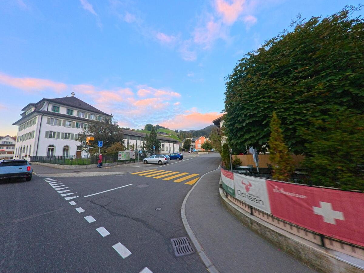 An einer markierten Kreuzung mit angrenzenden Gebäuden verläuft der Verkehr durch Rothenthurm (6418, Kanton Schwyz).