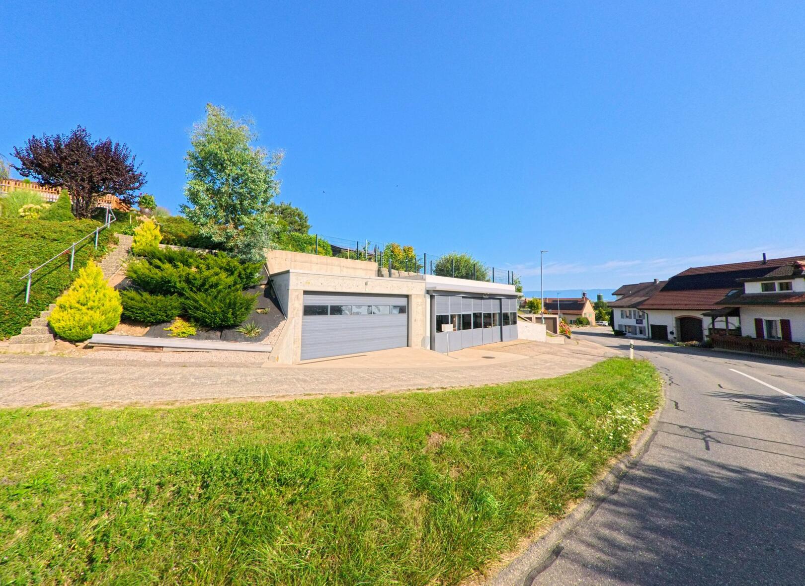 Am Strassenrand in Rovray (1463, Kanton Waadt) befindet sich eine moderne Garagenanlage mit bepflanzter Hangterrasse oberhalb.