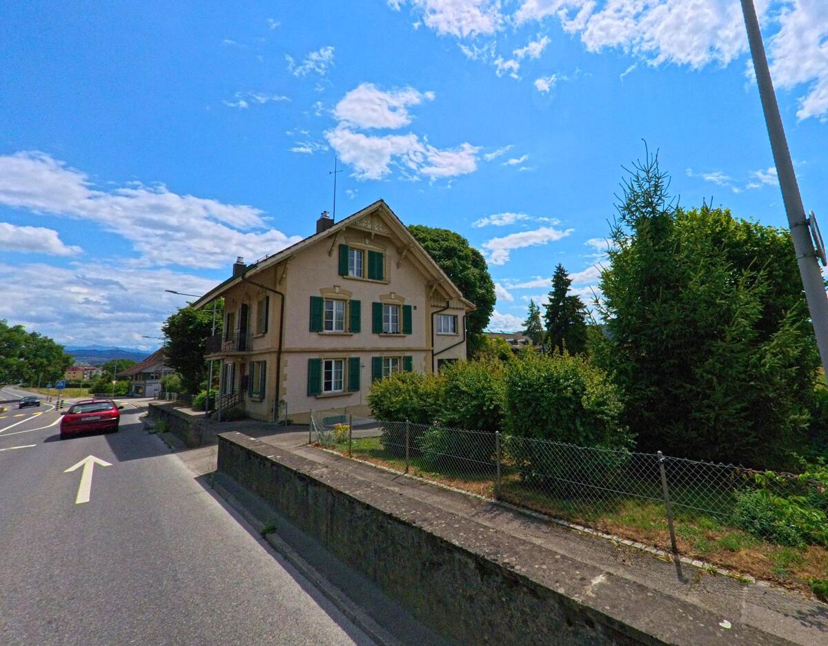 Am Rand einer leicht abfallenden Strasse in Rubigen (3113, Kanton Bern) steht ein älteres Wohnhaus mit grünen Fensterläden und gepflegtem Garten.