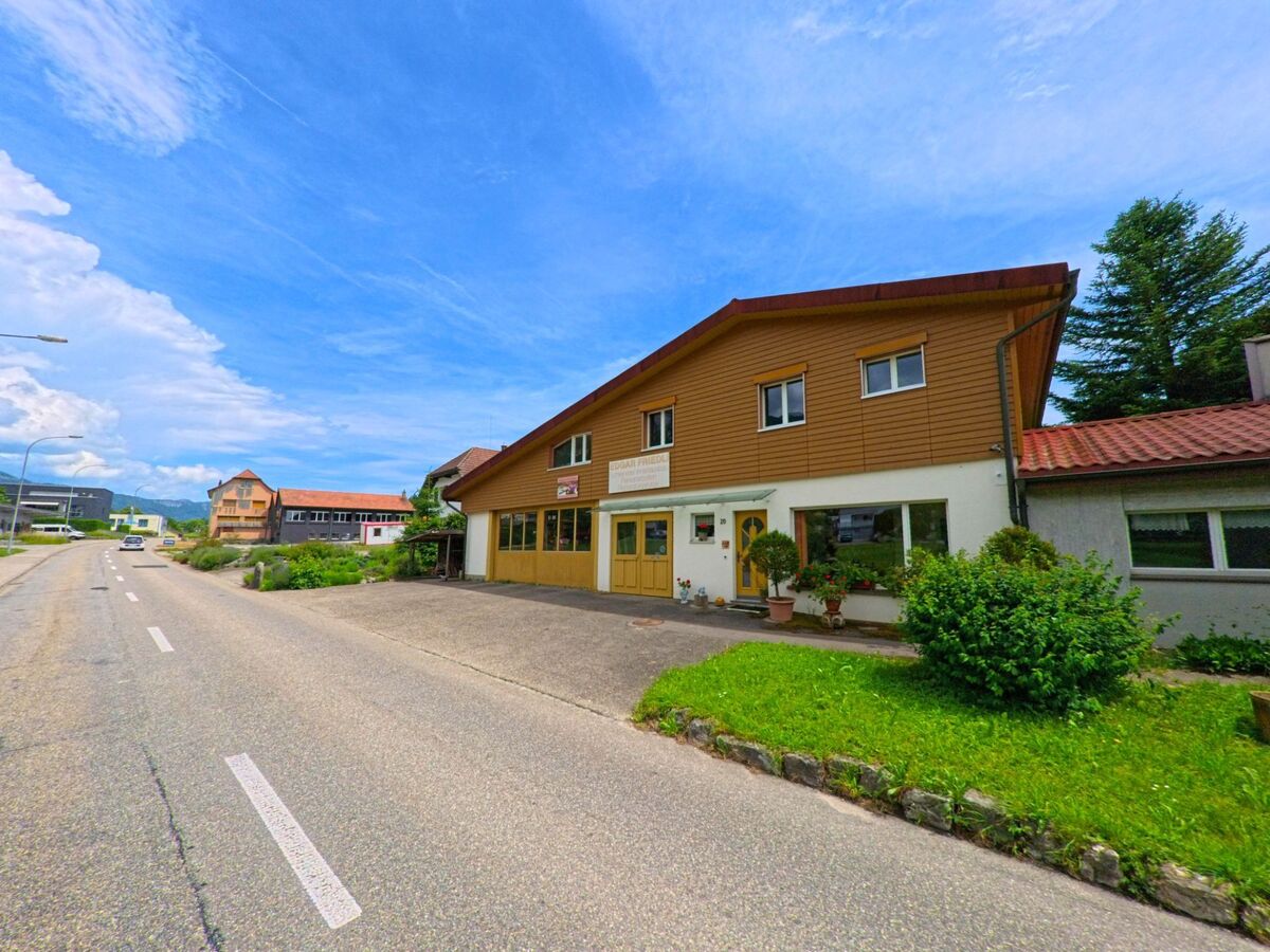 In Rüttenen im Kanton Solothurn (PLZ 4522) steht ein Gewerbegebäude mit gelber Fassade und Schreinerei an einer leicht ansteigenden Strasse.