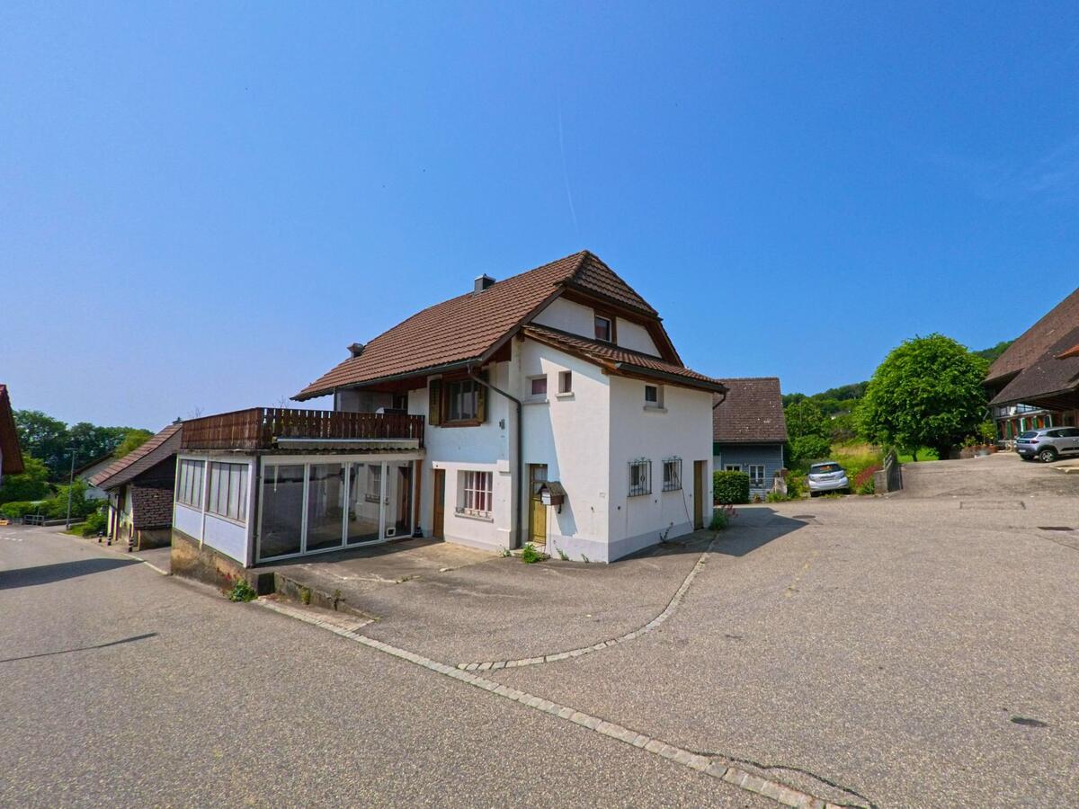 In einem ruhigen Wohngebiet von Rumisberg (4539, Kanton Bern) steht ein freistehendes Haus mit überdachtem Vorbau und grossem Balkon an einer leicht abfallenden Strasse.