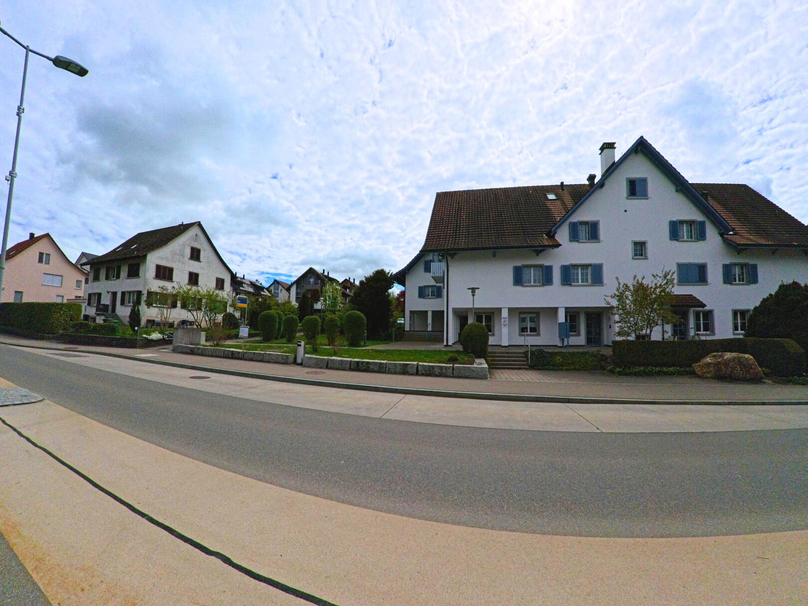 In Russikon (8332, Kanton Zürich) stehen entlang einer ruhigen Strasse mehrere gepflegte Wohnhäuser mit typischem Satteldach und Vorgärten.