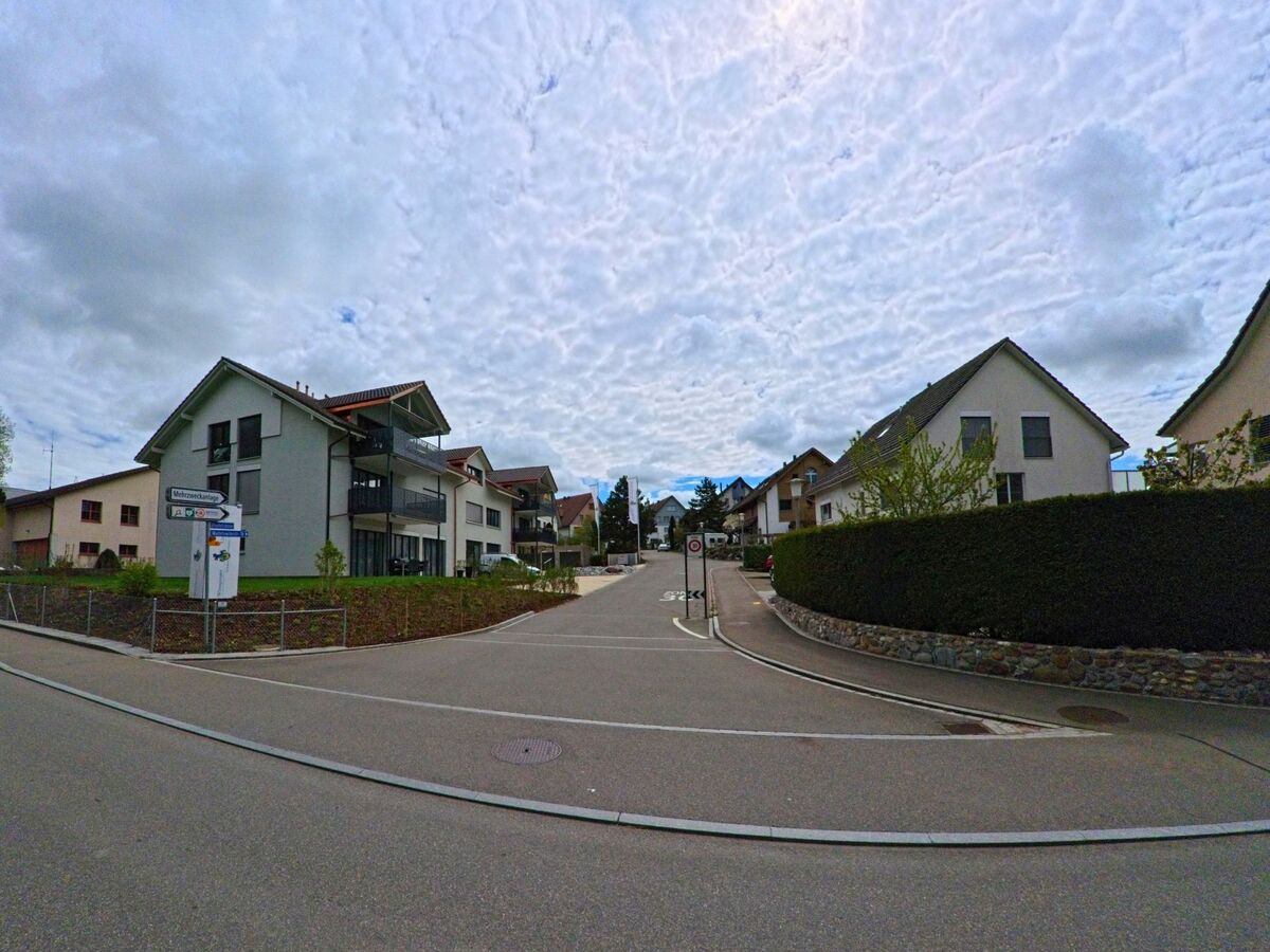 In einem modernen Wohnquartier von Russikon (8332 im Kanton Zürich) führen verkehrsberuhigte Strassen zwischen Neubauten und gepflegten Hecken entlang.