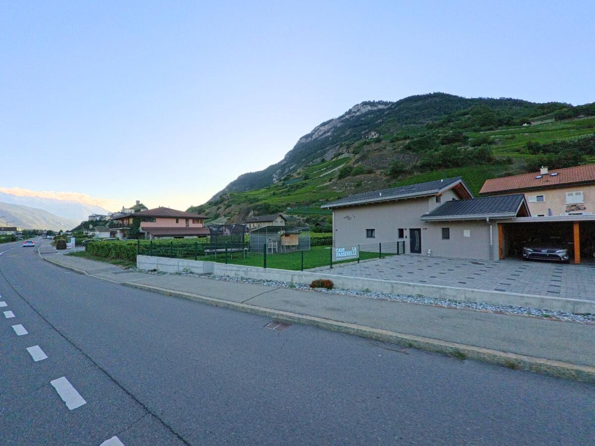 Am Ortsrand von Saillon (1913, Kanton Wallis) reihen sich Wohnhaeuser entlang der Strasse vor den steilen Weinberghaengen.