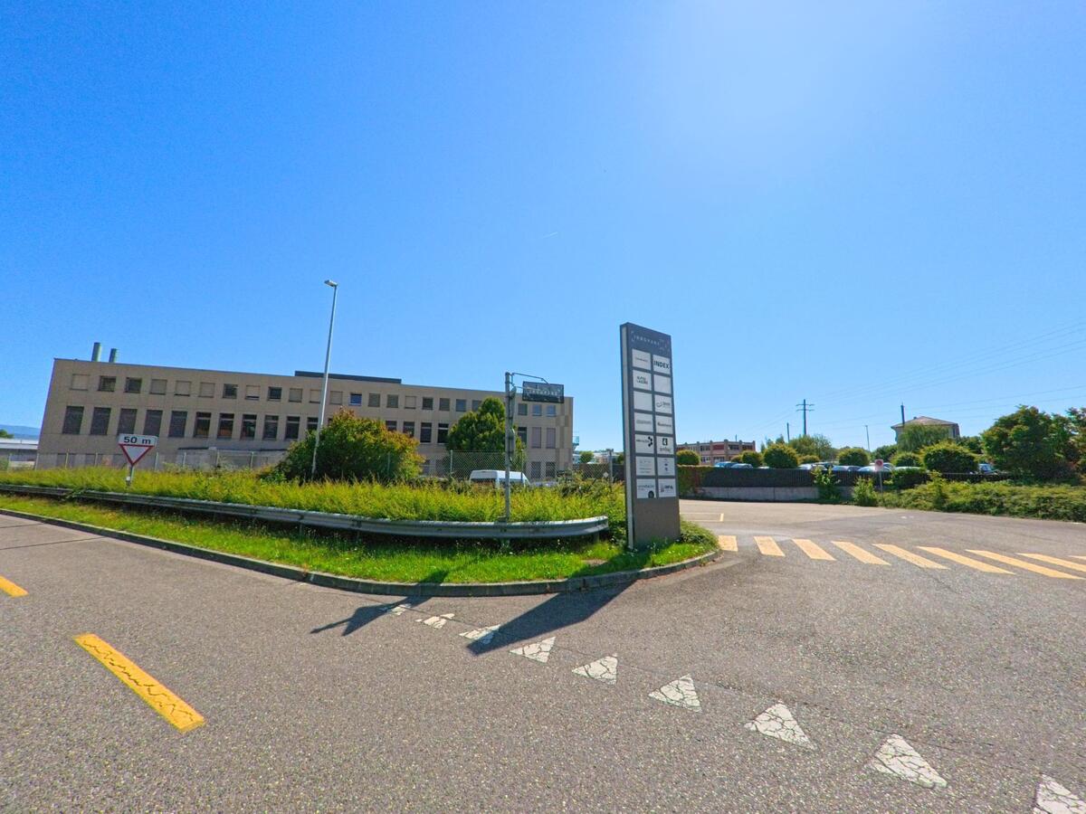 Vor einem grossen Gewerbegebaeude in Saint-Blaise (2072, Kanton Neuenburg) steht eine Hinweistafel mit den Namen verschiedener Firmen im Industriegebiet.