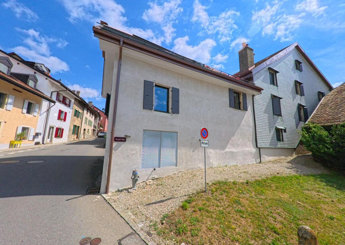 Die Grand Rue in Saint-Livres (1176, Kanton Waadt) wird von hellen Wohnhaeusern mit farbigen Fensterlaeden gesaeumt und wirkt ruhig und gepflegt.