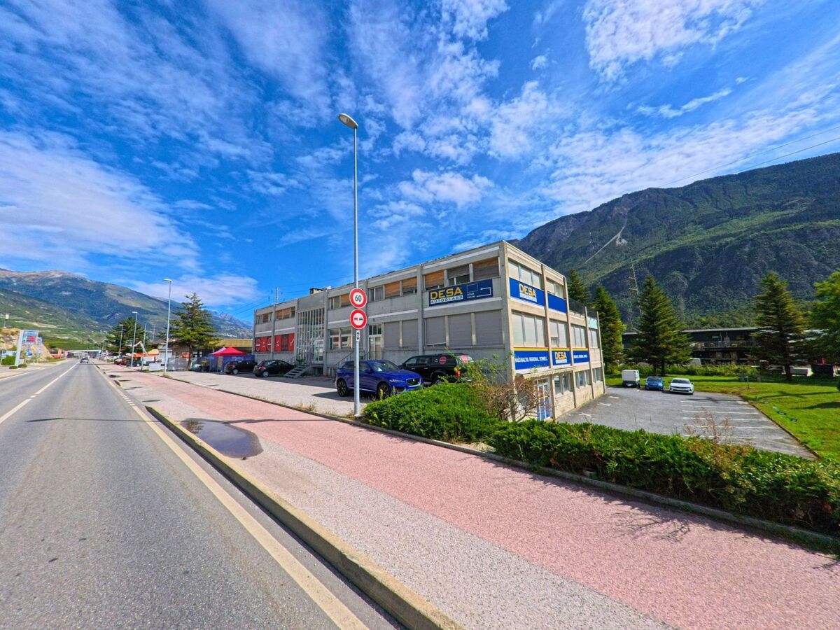 Ein Gewerbegebäude mit verschiedenen Firmen befindet sich an der Hauptstrasse von Salgesch (3970, Kanton Wallis) vor der Kulisse der umliegenden Berge.