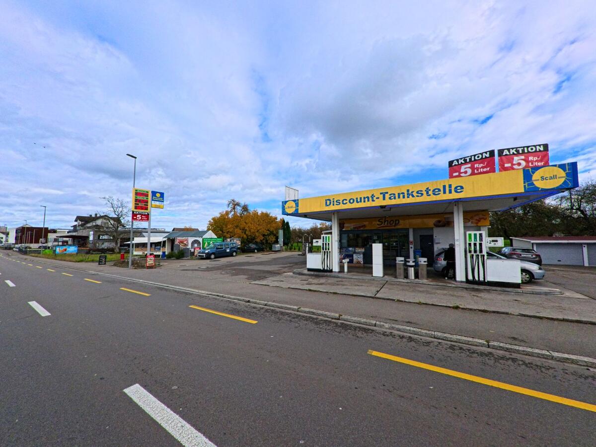 Eine Tankstelle mit Zapfsäulen und Shop liegt an einer Durchgangsstrasse in Salmsach (8599, Kanton Thurgau) unter weitläufigem Himmel.